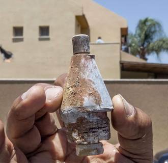 Image: An Israeli man holds up the remains of a rocket that damaged his house following a rocket attack by militants from the Gaza Strip