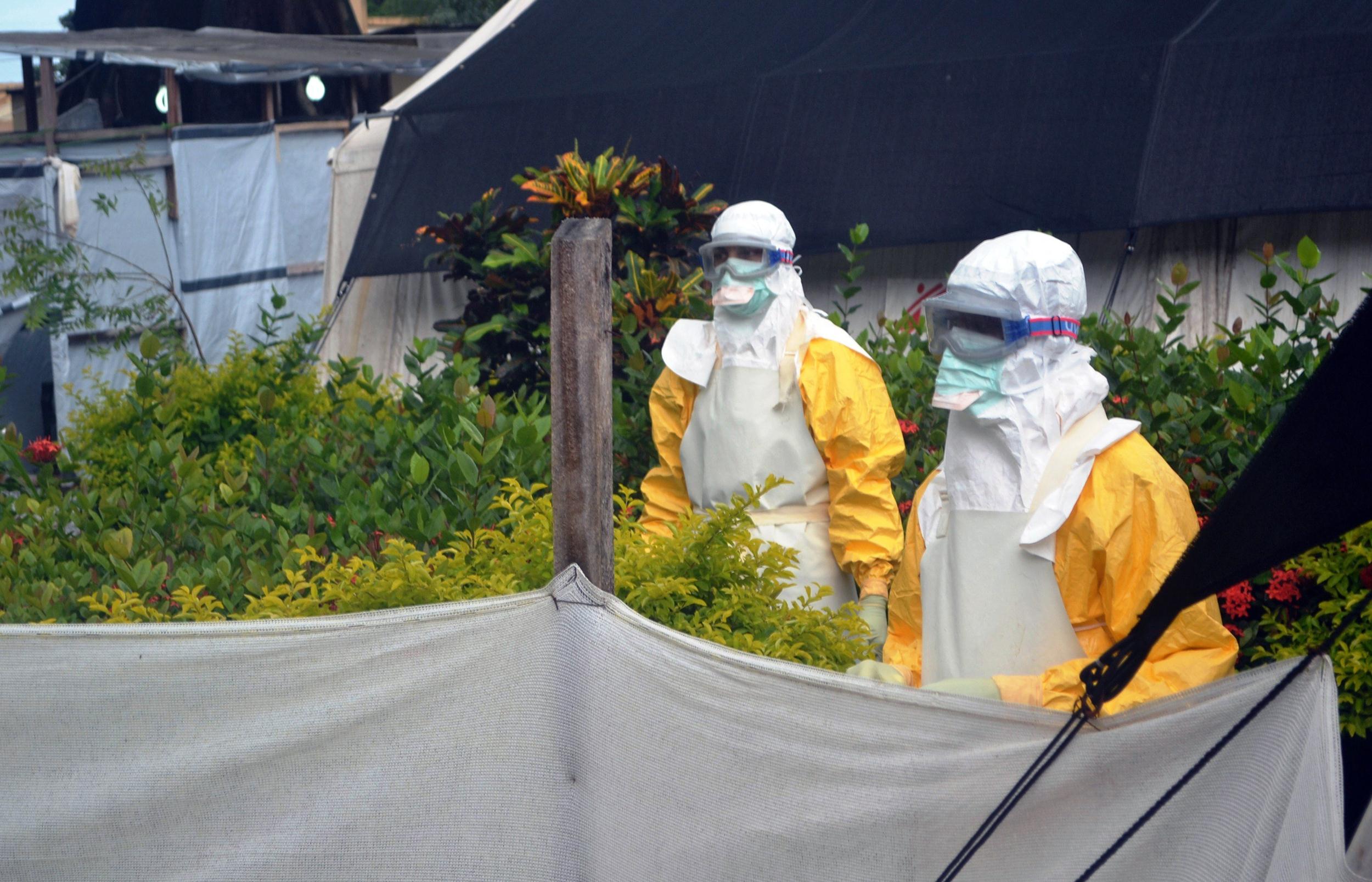 Image: Doctors Without Borders (MSF) personnel wearing protective gear walk outside the isolation ward of the Donka Hospital