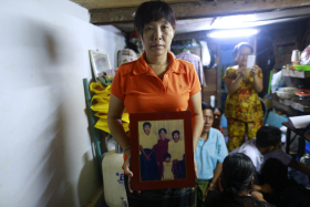 Than Dar, the wife of slain journalist Par Gyi, holds a family photograph showing herself, her husband and daughter posing with Aung San Suu Kyi at their home, in Yangon