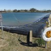 Field distribution water tank used in the fracking process of natural gas well drilling in DeWitt County, Texas, complete with life buoy and "No Swimming" sign.