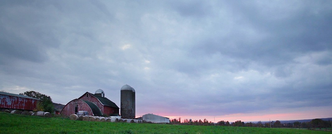 The sun sets behind a farm in Dryden, NY.