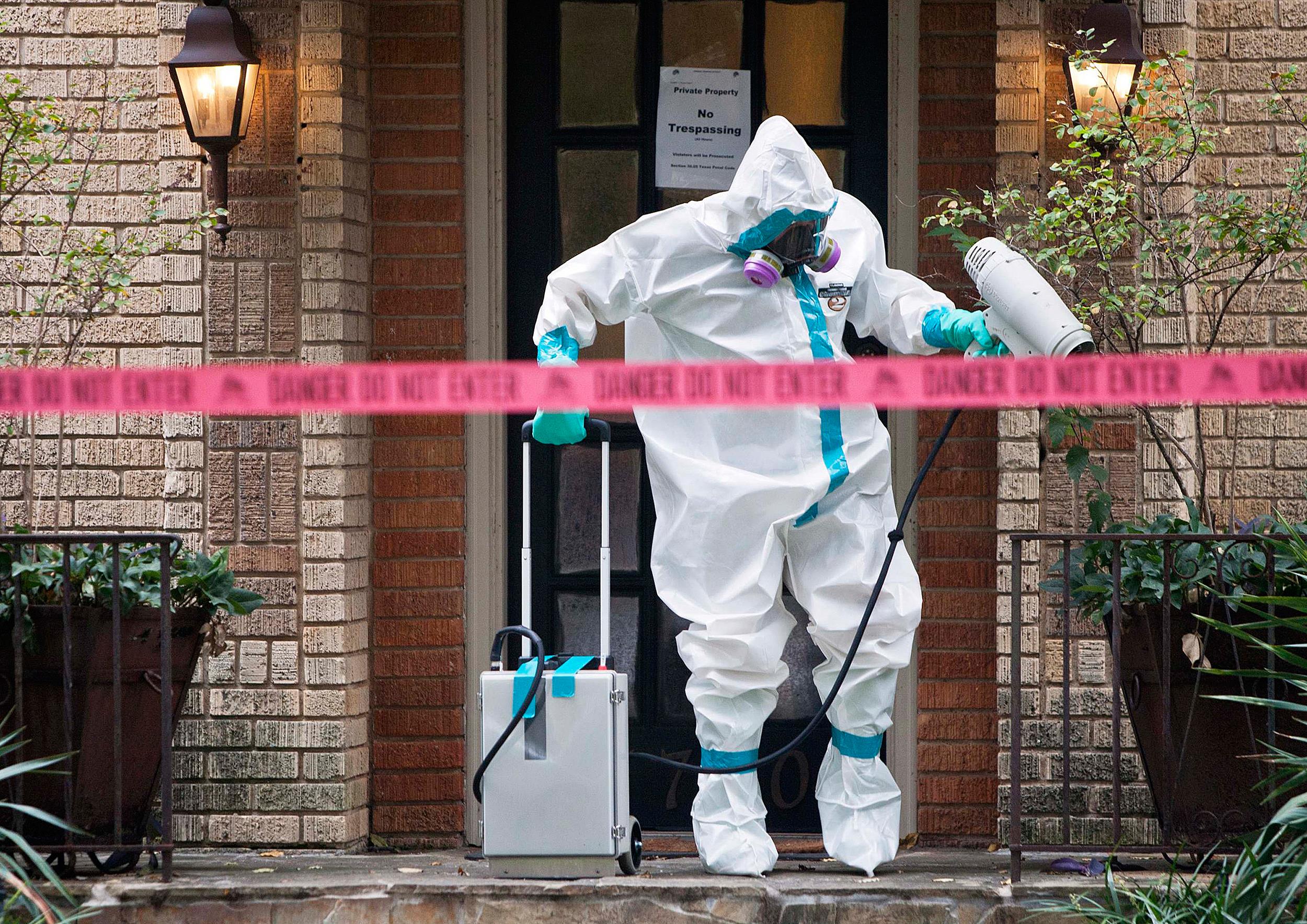 Image: A member of the CG Environmental HazMat team disinfects the entrance to the residence of a health worker at the Texas Health Presbyterian Hospital who has contracted Ebola in Dallas, Texa