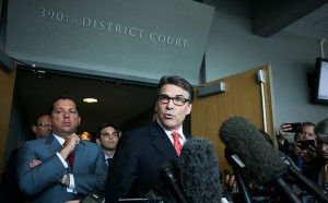 Texas Gov. Rick Perry, flanked by attorney J. Brett Busby (left), answers questions from reporters Thursday at the Blackwell-Thurman Criminal Justice Center in Austin.