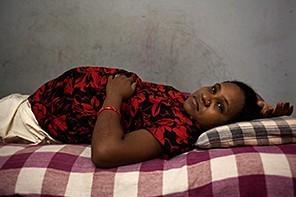 Vasanti, 30, rests in her bed in the surrogate house. During the pregnancy the surrogate mothers live together in a big house. (Serena de Sanctis)