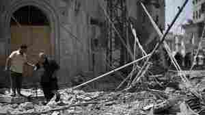 Palestinian men walk amidst debris following an Israeli military strike in Gaza city, on July 23, 2014.