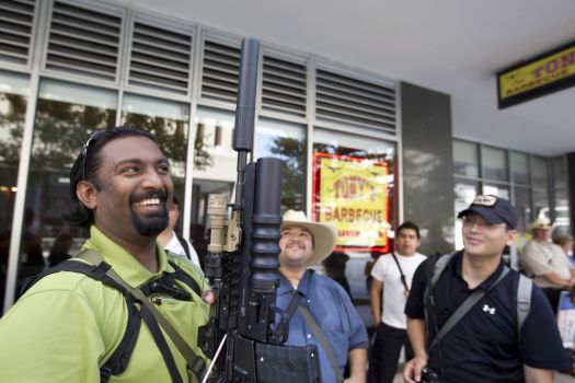 Bibin Thomas, 27, of Missouri City holds up his AR-15 rifle as he joined a group of about 25 people with the pro-gun rights organization, Come and Take it Houston, as they assembled at City Hall and walked through downtown carrying their guns as part of a rally Thursday, July 4, 2013, in Houston. 
"This is a Come and Take it Houston walk to help inform citizens about the gun laws here in Texas," co-organizer Kenneth Lindbloom said. "In Texas there are no restrictions on the open cary of long arms like rifles and shotguns and we want people to realize that in the hands of good people, guns are not dangerous and they don't kill people. When good people have guns it serves as a deterrent to stop crime."( Johnny Hanson / Houston Chronicle ) Photo: Houston Chronicle