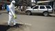 A Liberian health worker disinfects a street corner