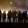 Police walk through a cloud of smoke as they clash with protesters in Ferguson, Mo., this summer.