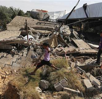 Image: Palestinians inspect the rubble of a house after it was hit by an Israeli missile