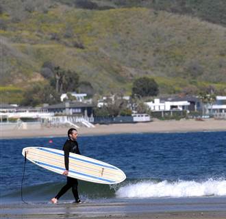 Image: A surfer heads toward the water at in Malibu