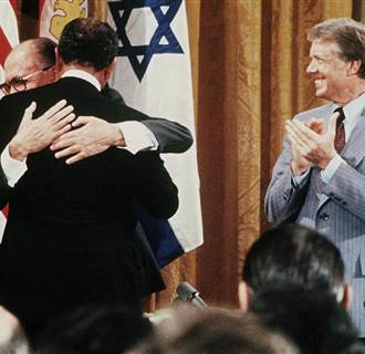 Image: Egyptian President Anwar al-Sadat and Israeli Premier Menachem Begin hug as U.S. President Jimmy Carter looks on