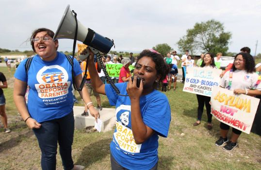 Deborah Alemu (center) and Maria Reza (left) lead protestors in a chant demanding the release of immigrants held at a facility in Karnes City on Saturday, Oct. 11, 2014. About 100 protesters rallied in front of the Karnes County Residential Center to demand the closing of the facility and for the release of immigrants detained at the center. Photo: Kin Man Hui, San Antonio Express-News / ©2014 San Antonio Express-News