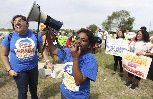 Deborah Alemu (center) and Maria Reza (left) lead protesters chanting for the release of immigrants at the Karnes County Residential Center in Karnes City. About 100 people came from Austin, San Antonio, Dallas and Houston for the rally. Photo: Photos By Kin Man Hui / San Antonio Express-News / Â©2014 San Antonio Express-News