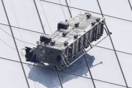 A firefighter reaches through a cut-out window into a dangling work basket to rescue two window washers from outside 1 World Trade Center in New York, Wednesday, Nov. 12, 2014. The two window washers were trapped for more than an hour.