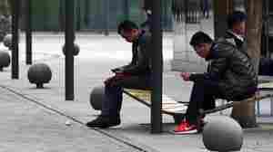An international tariff on high-tech goods could be rewritten, thanks to negotiations in China. Here, men use smartphones in Beijing last month, days after Apple released its iPhone 6 in the Chinese market.
