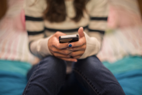 Close up of teenage girl texting on mobile in bedroom