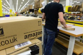 An employee places packed goods on a conveyor belt for shipment at Amazon's Brieselang logistics center west of Berlin on Nov. 11, 2014.