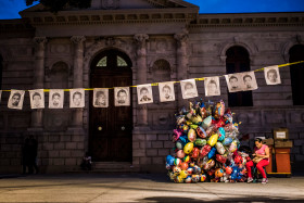 CHINPALCINGO, MEXICO - 31 OCTOBER 2014:Holding portraits of the missing students in Chinpalcingo Zocalo (Main Square) while a woman sell ballons for the Dia de los Muertos. Chilpancingo de los Bravo is the capital of Guerrero State and is located just 14 km from the Raul Isidro Burgos de Ayotzinapa College. This city is the head of the demonstrations against the government for the lack of proof and responsibilities for the 43 disappeared students on September 26th in Iguala.