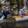 A man pushes a woman and a dog in a boat a boat after their neighborhood experienced flooding due to Hurricane Sandy, on October 30, 2012, in Little Ferry, New Jersey.