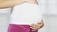 A pregnant woman holds her belly.