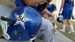 Edna High School football players honor their teammate Noah Ortiz with a decal of his number 50 jersey on their helmets.