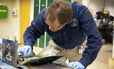 NTSB Materials Engineer Matt Fox examines the casing from the battery involved in the JAL Boeing 787 fire incident.