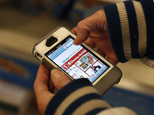 FILE - In this Nov. 28, 2014 file photo, a Target shopper uses her iPhone to compare prices at Wal-Mart while shopping after midnight in South Portland, Main...