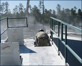 Silica dust cloud by worker delivering sand from sand mover to transfer belt - Photo credit-NIOSH
