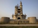 In this Oct. 18, 2014, photo, a man walks past the shell of a castle-like building that was once destined to be part of Asia's biggest amusement park in Beijing, China. Work halted on the project in 1998 due to financial problems and the site has been left as it is until 2013 when developers demolished other parts of the massive park for redevelopment. The castle-like building however remains untouched and a reminder of better times in that part of Beijing's periphery. (AP Photo/Ng Han Guan)