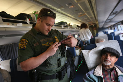A United States Border Patrol agent checking passenger identifications on an Amtrak train in Depew, N.Y., in June.