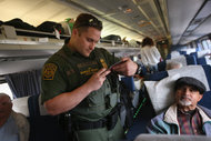 A United States Border Patrol agent checking passenger identifications on an Amtrak train in Depew, N.Y., in June.