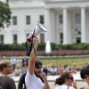 A protester uses a megaphone to shout sl