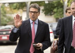 Gov. Rick Perry holds his Texas driver's license and his wallet as he heads to a west Austin early voting site on October 30, 2013.
