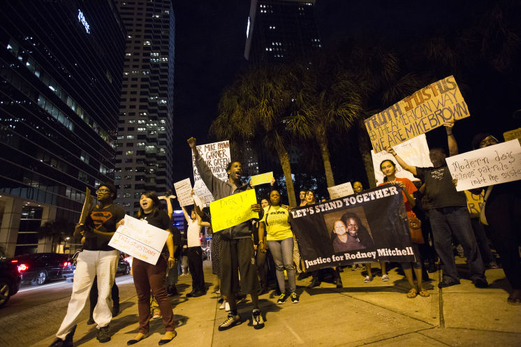   Ali Muhammad, 26, center, of Tampa leads the crowd of activists in chants at Lykes Gaslight Park. Protesters from the Tampa Bay area gather in Lykes Gaslight Park demanding justice for the deaths of Eric Garner of New York and Michael Brown of Ferguson, Missouri both who were killed by police officers while unarmed in downtown Tampa on Friday, December 5, 2014.
