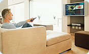 A man using his remote control for his flat screen tv.