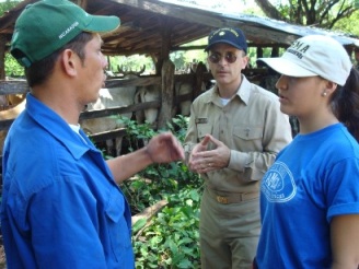 A veterinarian from the Nicaraguan Ministry of Agriculture and Forestry (left) and LCDR Gregory Langham, veterinarian, U.S. Public Health Service (center) discuss characteristics of two different medications for deworming cattle; the young woman is serving as an interpreter.