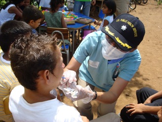 CDR Monica Rueben applies five-percent sodium fluoride varnish to an adult who is waiting in line to see health care providers at a temporary dental and medical clinic at the Costa Brava School near Acajutla, El Salvador. 