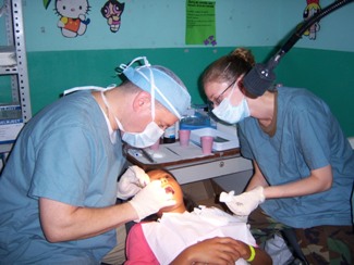 LT Charles Brucklier, HHS U.S. Public Health Service Commissioned Corps dental hygienist, applies a dental sealant to a young girl in Acajutla, El Salvador, while SSGT April Paulson, a dental assistant from the U.S. Air Force, assists. (Photo provided by LT Charles Brucklier, USPHS.)
