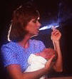 mother smoking a cigarette while holding an infant