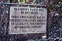 warning sign on chain-link fence reading "hazardous waste site - do not enter"