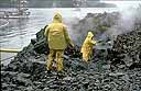 Workers spray oiled rocky shore with hot water
