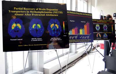 Posters of drug abuse statistics and graphics are displayed at the press event