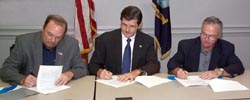 Steve Strom, Member of the National Shipbuilding Research Program Executive Control Board; John Henshaw, then-Assistant Secretary of Labor and Paul Robinson, Member of the American Shipbuilding Association Board of Directors signing two separate Alliances on July 15, 2003.