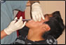 Photo Thumbnail:While in Peru, CDR Maria-Paz Smith, a dentist, performs an extensive dental exam on a patient at the Huacho clinic.