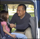 Photo: A father fastening his daughter in a child safety seat.
