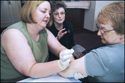 Photo: Lorna Will (left) and Jacqueline Kowalski learn how to deliver smallpox vaccine safely and efficiently as trainer Judy Gibson observes. Photo by James Gathany.
