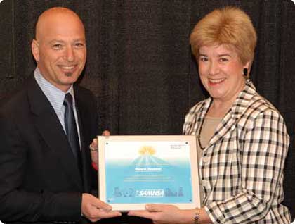 photo of Howie Handel (left) with A. Kathryn Power (right) holding SAMHSA plaque between them