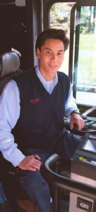 Photo of driver at the wheel of the bus.