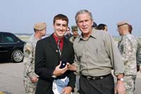 President George W. Bush presented the President’s Volunteer Service Award to Benny Smith, Jr., 17, upon arrival at the airport at Pope Air Force Base, North Carolina, on Tuesday, July 4, 2006.  Smith is a volunteer for a variety of programs at Fort Bragg, including Army Community Service and Happy Hats.  To thank them for making a difference in the lives of others, President Bush honors a local volunteer, called a USA Freedom Corps greeter, when he travels throughout the United States.  President Bush has met with more than 500 individuals around the country, like Smith, since March 2002.