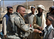 photo of a National Guard member handing out crayons to a boy in Afghanistan